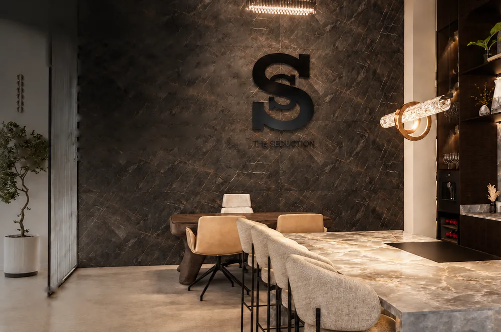 Interior del showroom de The Seduction: pared de mármol con el logo S, una mesa de comedor y una barra de ónice
