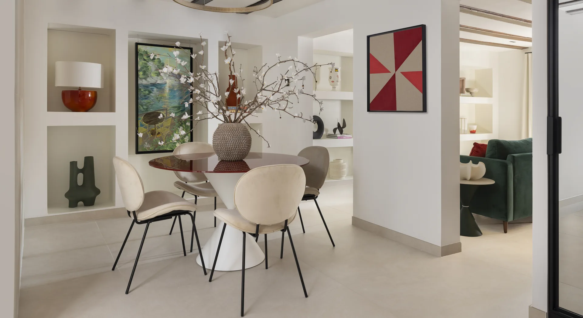 Comedor con mesa redonda, sillas blancas y arte contemporáneo