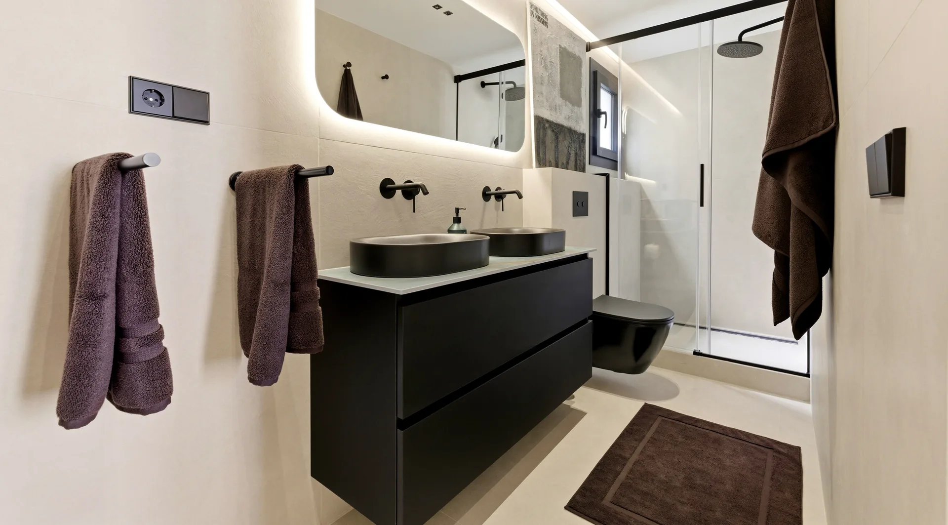 Baño con doble lavabo negro y espejo retroiluminado